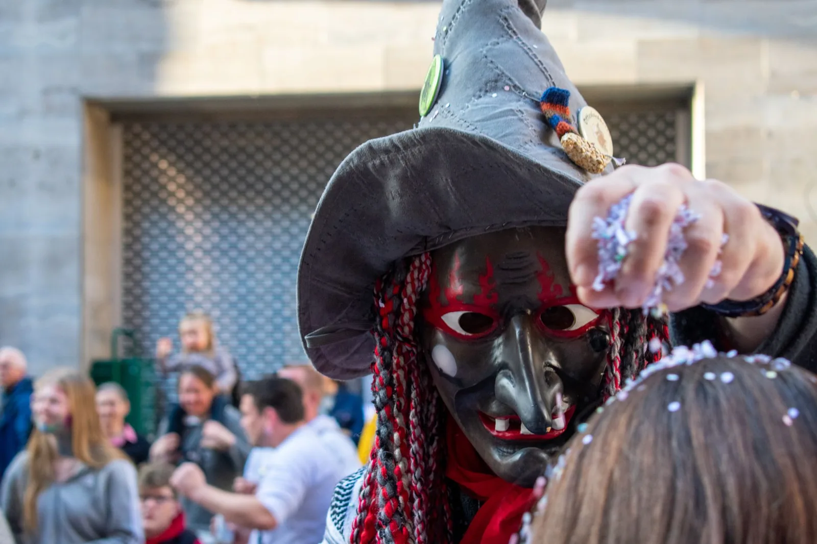 Sorcière masquée de la Fasnet lançant des confettis dans la foule pendant un cortège de carnaval