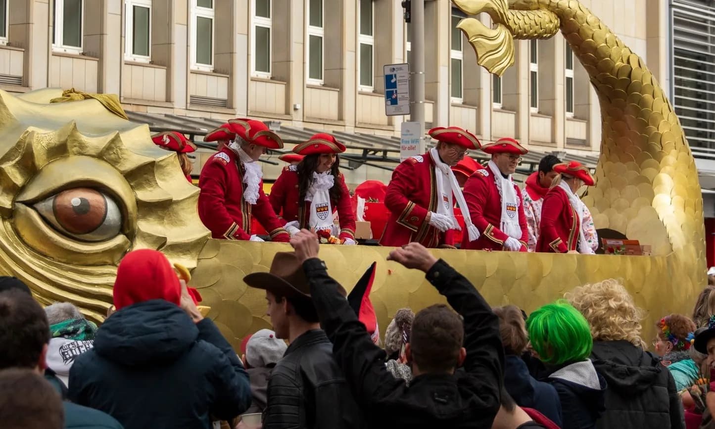 Char doré du cortège du Rosenmontag à Cologne, avec des Funkenmariechen et des gardes en uniforme rouge devant la foule costumée