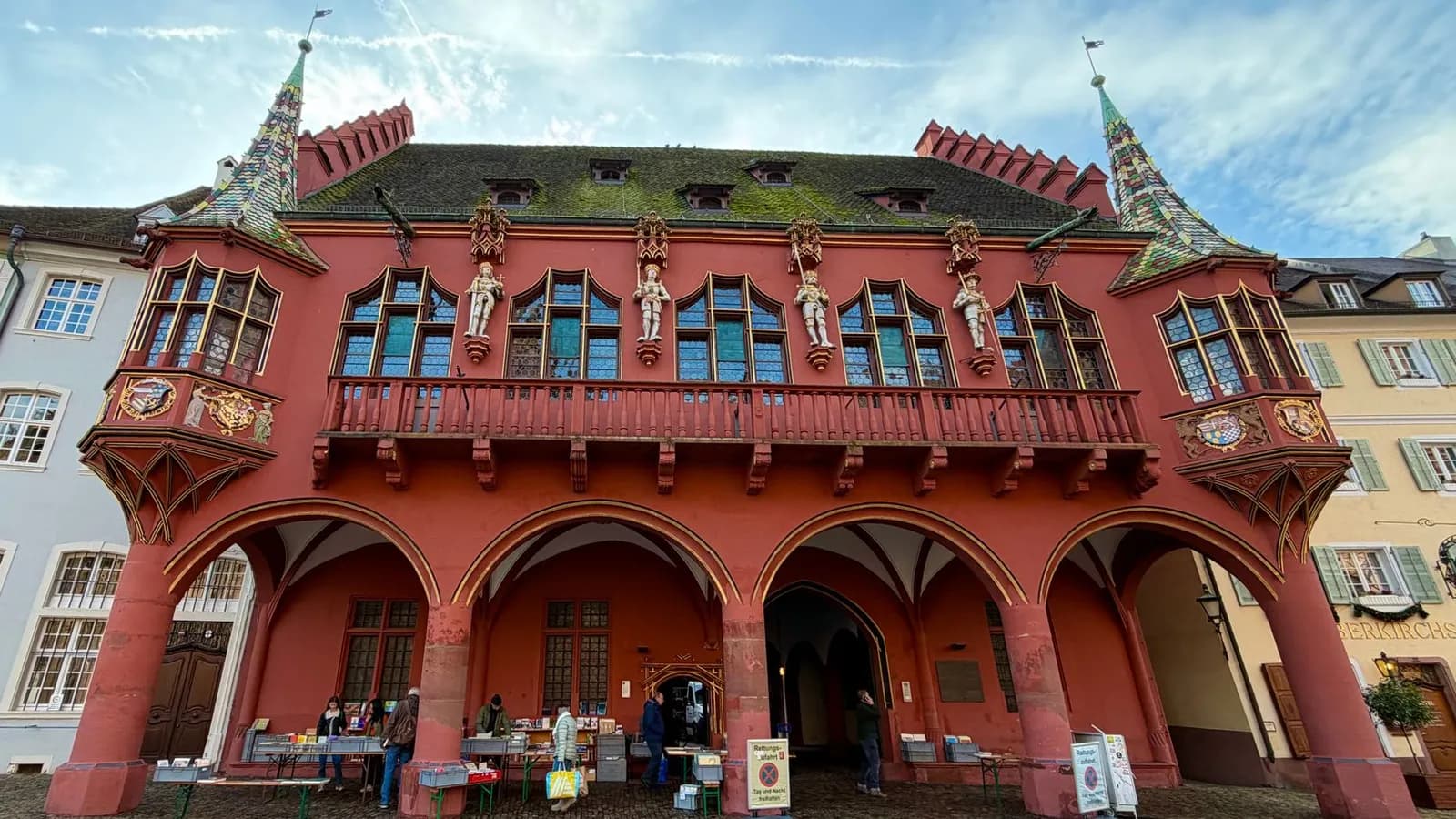 La façade rouge de l'Historisches Kaufhaus et les étals du marché sur la Münsterplatz de Fribourg-en-Brisgau