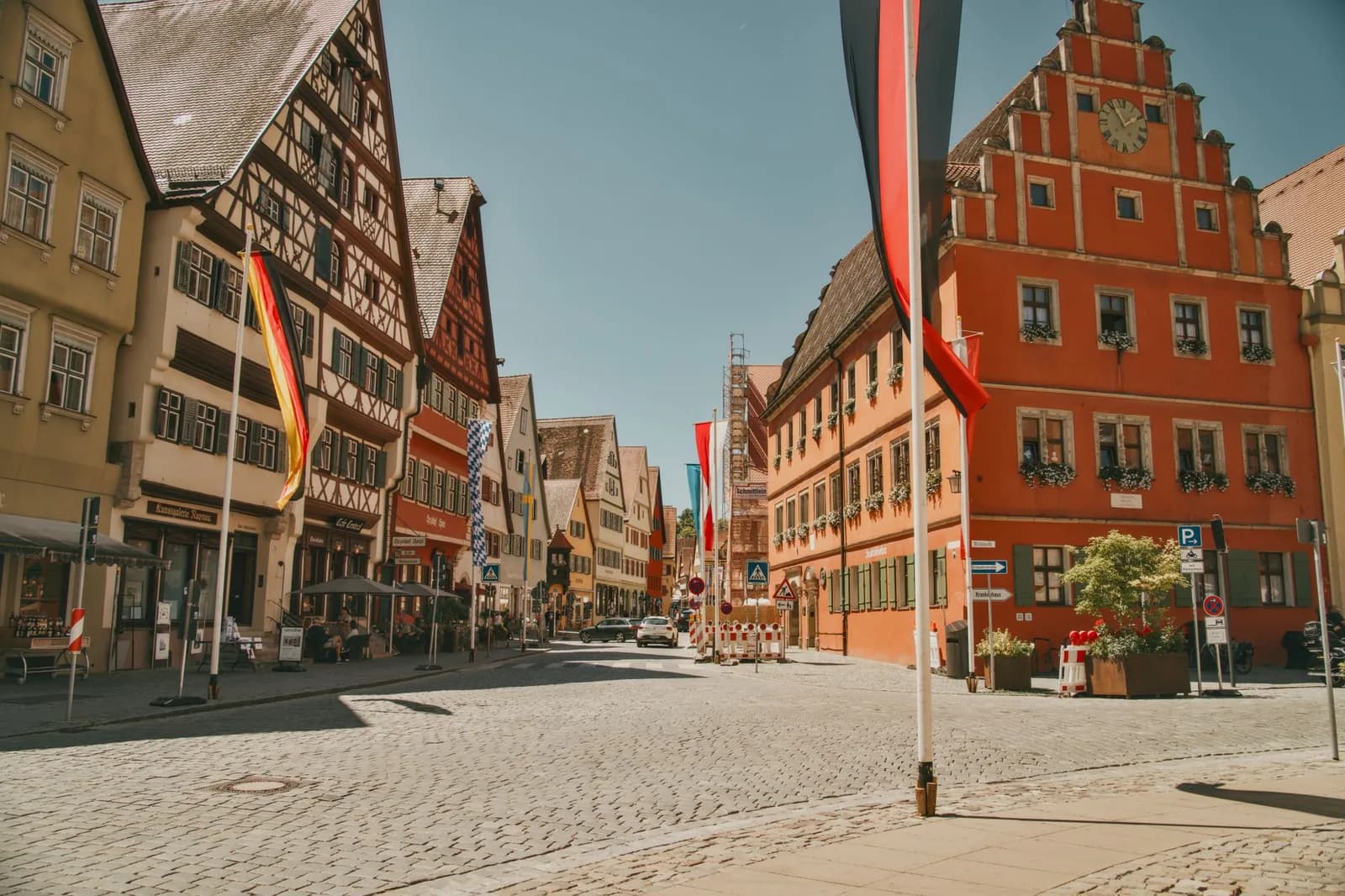 Rue pavée d'une vieille ville allemande à colombages, avec des drapeaux allemands et une maison rouge à pignon à gradins