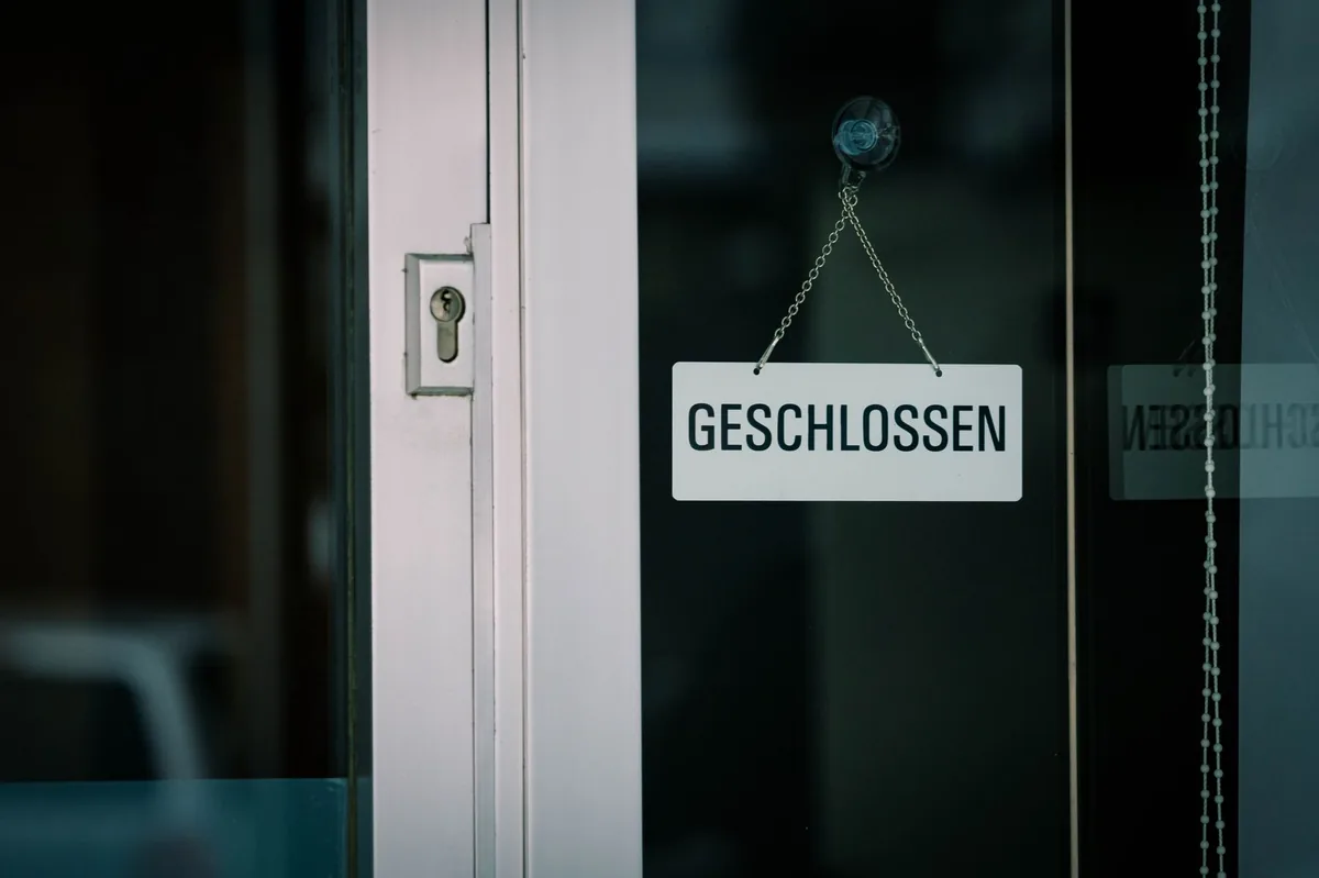 Panneau Geschlossen (fermé) suspendu à la porte vitrée d'un commerce en Allemagne