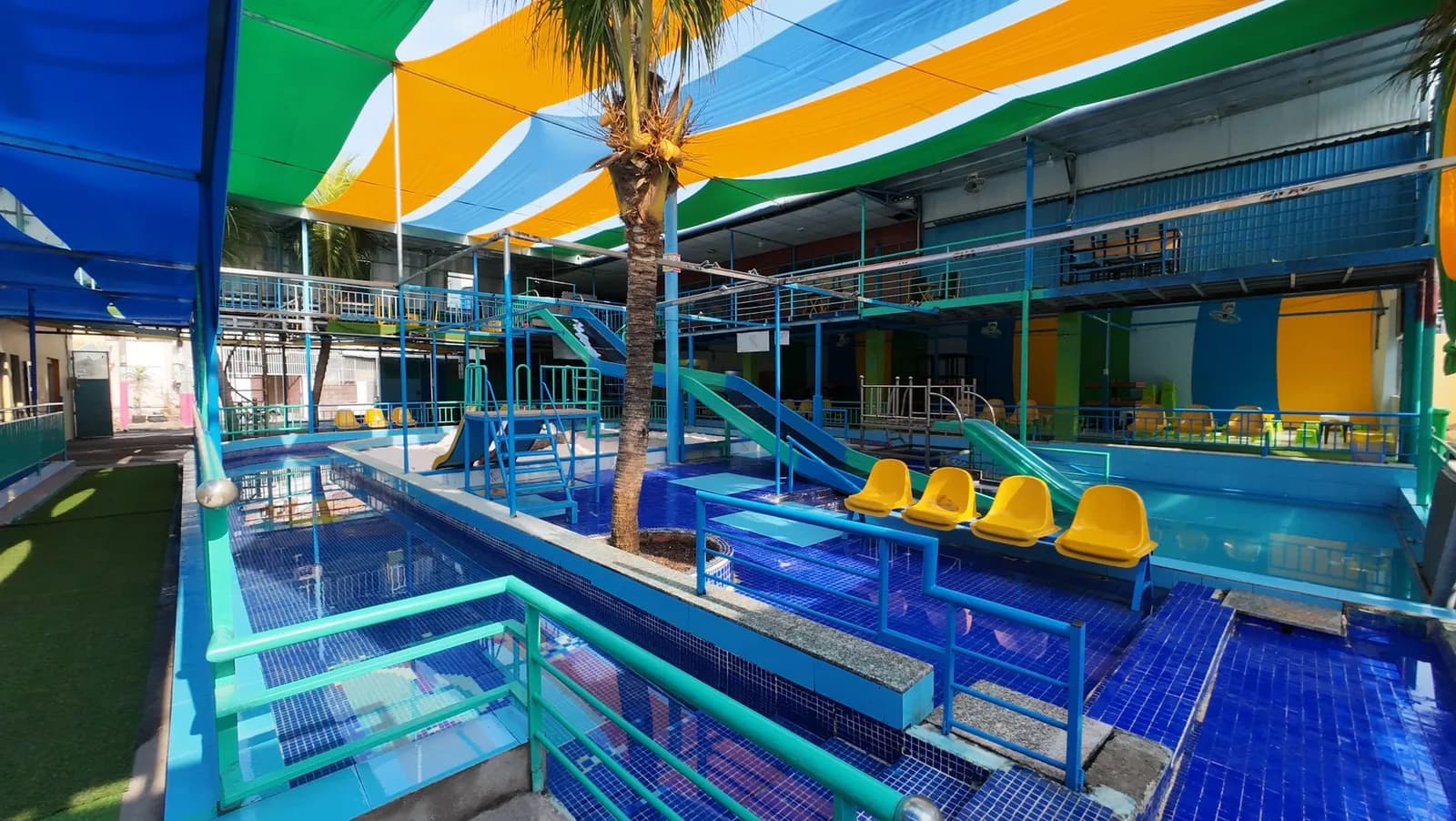 Aire de jeux aquatique pour enfants avec petits bassins, toboggans et voiles colorées